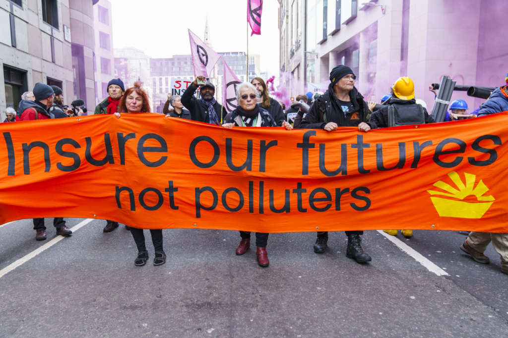 Protesters walk with banner reading 'Insure Our Futures Not Polluters'