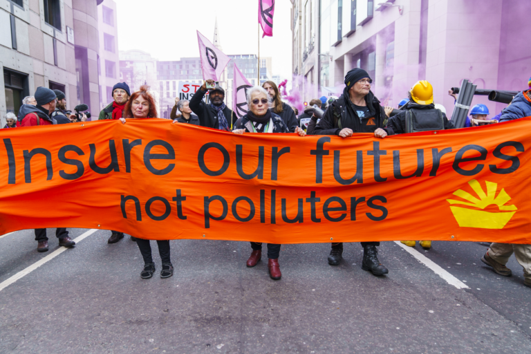 Protesters walk with banner reading 'Insure Our Futures Not Polluters'